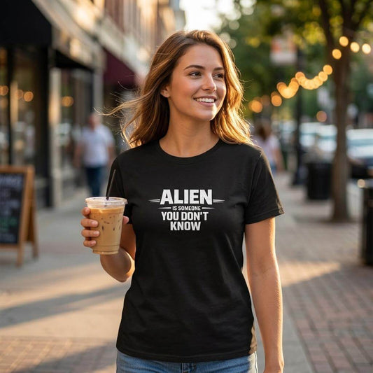 Urban Identity Graphic T-shirt med motiv "ALIEN YOU DON’T KNOW" i en stadsmiljö med en kvinna som håller en drink.