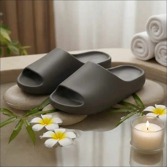 Recovery Slide – Lätta anti‑glid slides i brunt med mjukt EVA‑material, placerade på en sten med blommor och ett ljus.