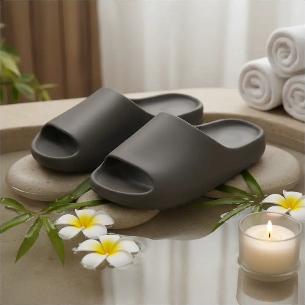 Recovery Slide – Lätta anti‑glid slides i brunt med mjukt EVA‑material, placerade på en sten med blommor och ett ljus.