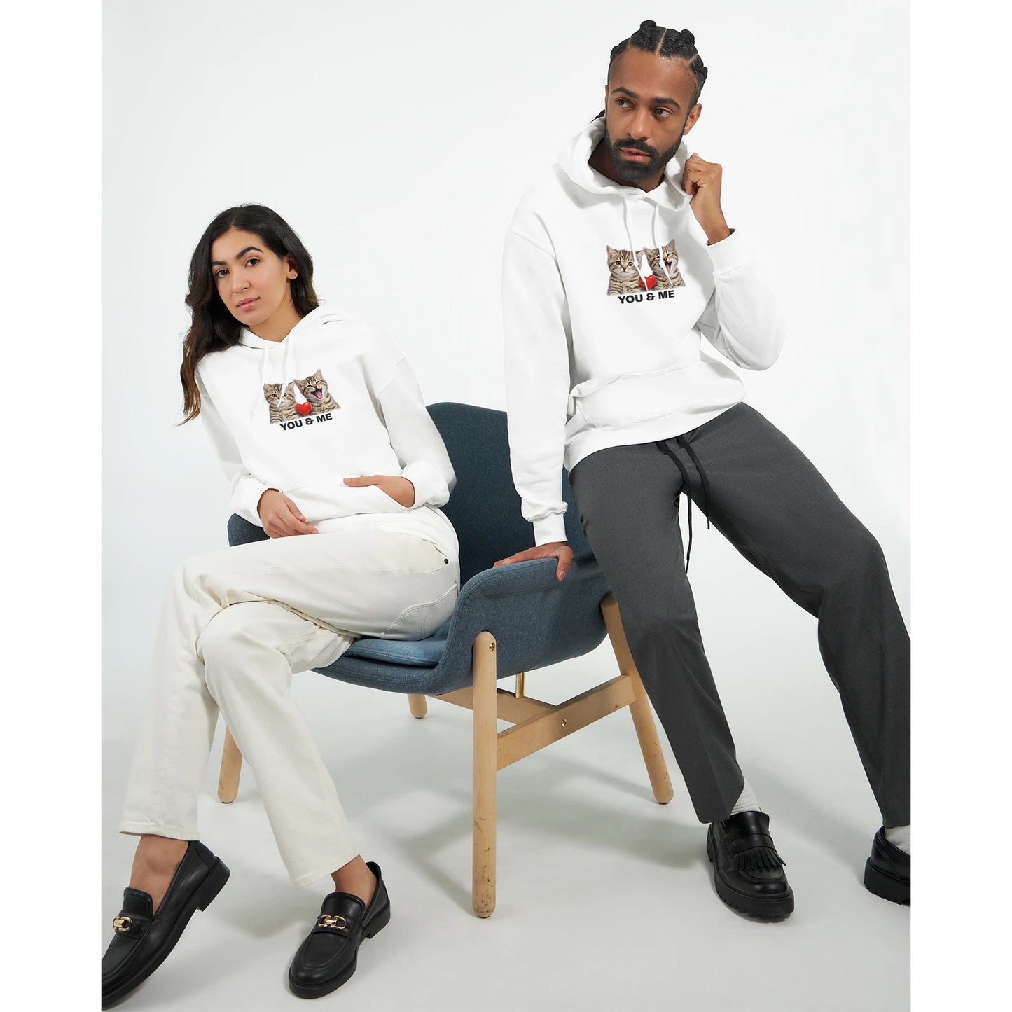Mjuk Hoodie med Katter och Du Jag Text, två modeller sittande i en stol med hoodie som visar kattansikten och text.