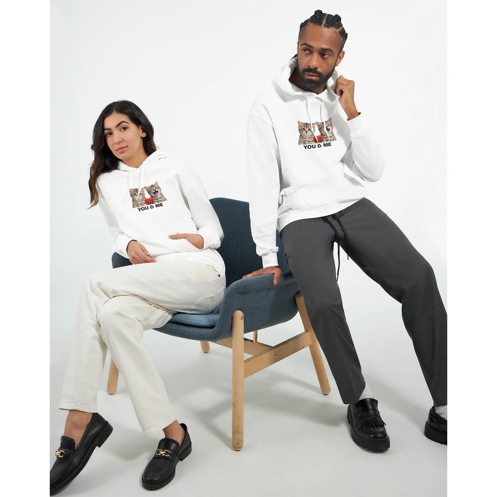 Mjuk Hoodie med Katter och Du Jag Text, två modeller sittande i en stol med hoodie som visar kattansikten och text.