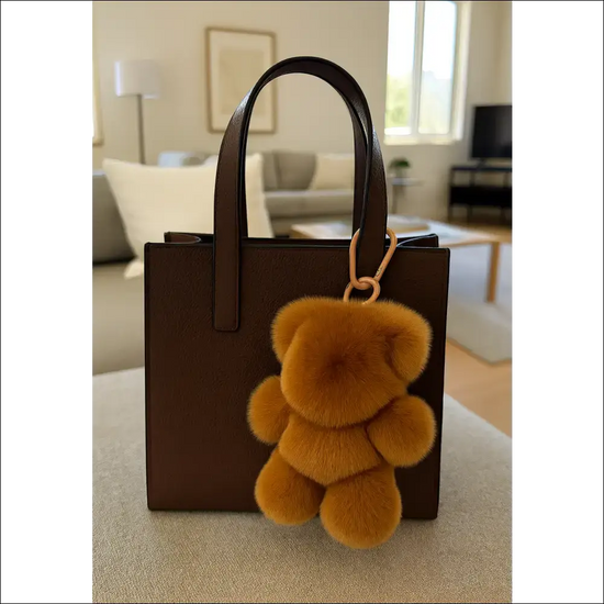 Bag Charm – Mjuk Teddy Nyckelring 18 cm hänger på en brun väska i ett stilrent rum