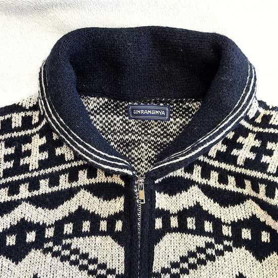 Stickad herrkofta med rullnacke i nordiskt Fair Isle-mönster, svart och vit design.