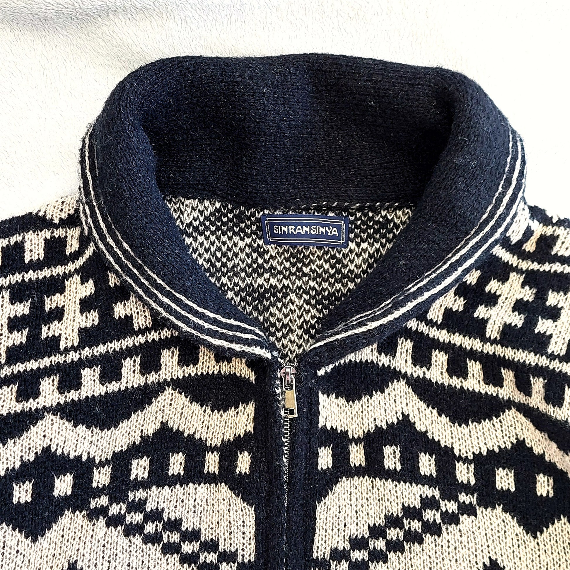 Stickad herrkofta med rullnacke i nordiskt Fair Isle-mönster, svart och vit design.