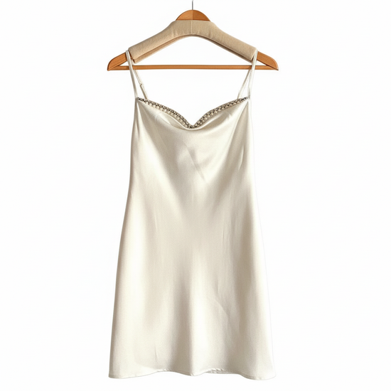 Kort vit klänning med pärlor – elegant mini silhuett och subtil glamour i satin.