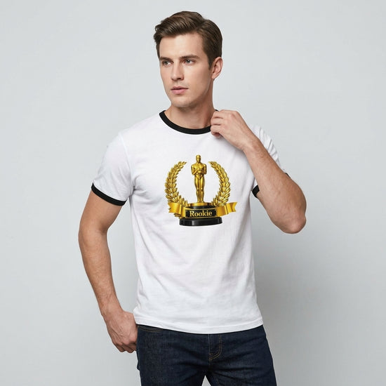En man bär en vit ringer-t-shirt med svart kontrast som har ett retro trophy-motiv och texten Rookie T-shirt.