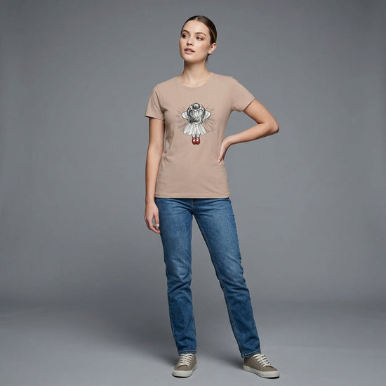 Kvinna i mjuk t-shirt med illustration av ballerina och röda dansskor, står på grå bakgrund.