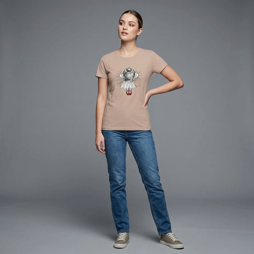 Kvinna i mjuk t-shirt med illustration av ballerina och röda dansskor, står på grå bakgrund.