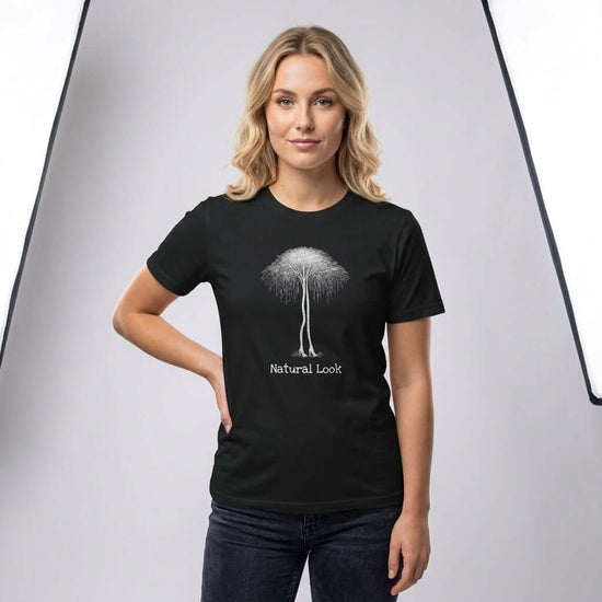 Birch Trees in Heels – Surrealism Art Tee featuring a woman in a black shirt with a tree design and 'Natural Look' text.