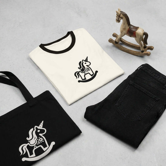 Magic Unicorn T-shirt med retro Dalarna-design, en gunghäst och en svart tygväska.