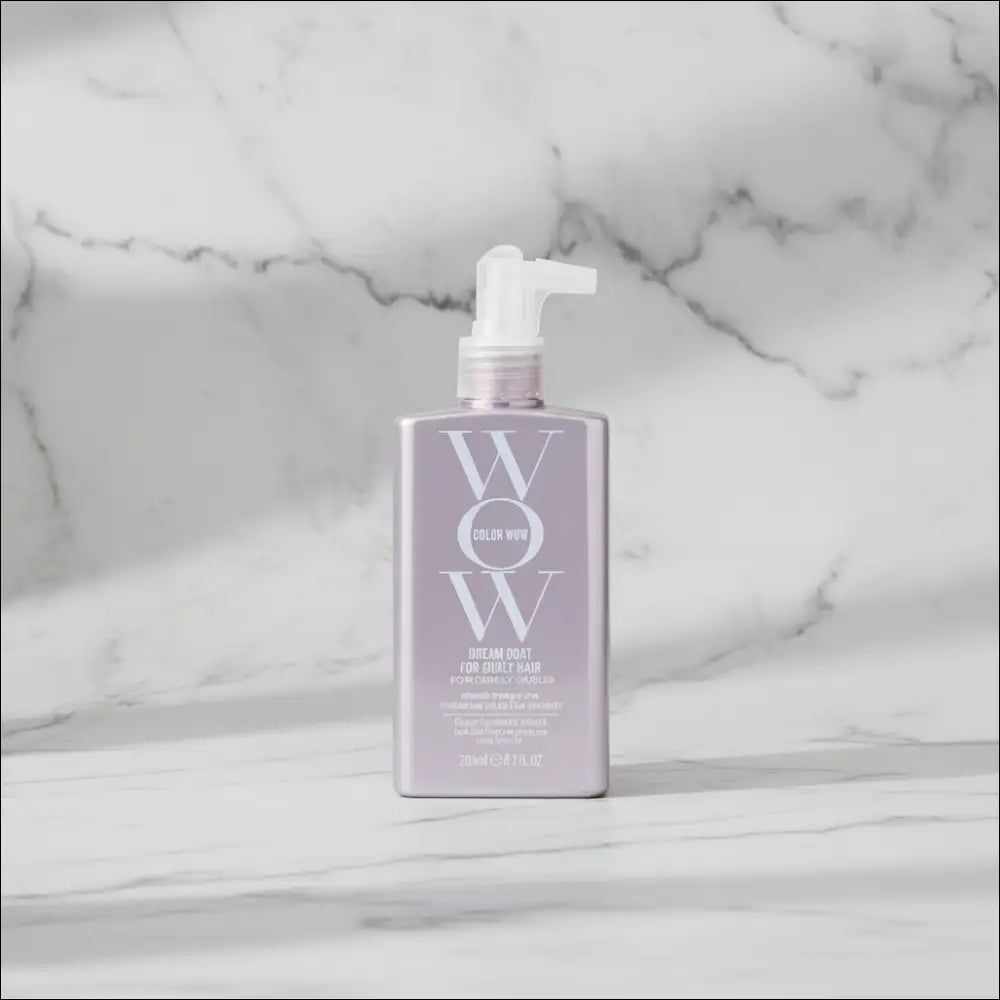 WOW Dream Coat för lockigt hår i grårosa flaska på marmor bakgrund.