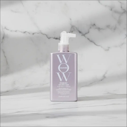 WOW Dream Coat för lockigt hår i grårosa flaska på marmor bakgrund.